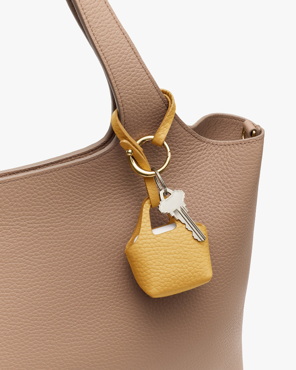 Keychain with small pouch hanging on a textured tote bag handle.
