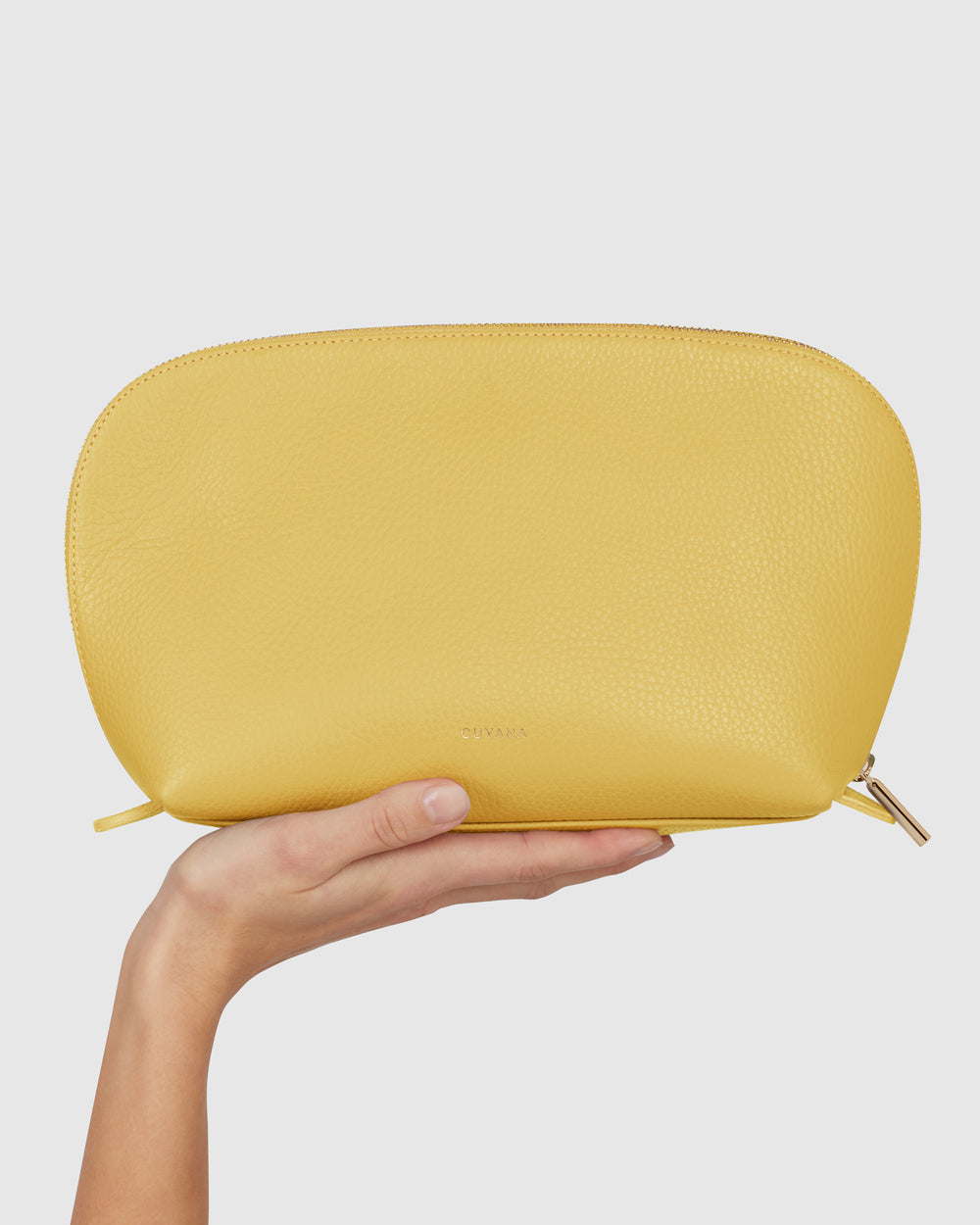 Person holding a pouch against a plain backdrop.
