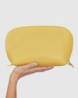 Person holding a pouch against a plain backdrop.