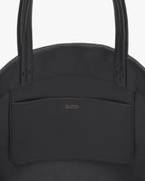 Close-up of a structured handbag with a pocket and two handles.