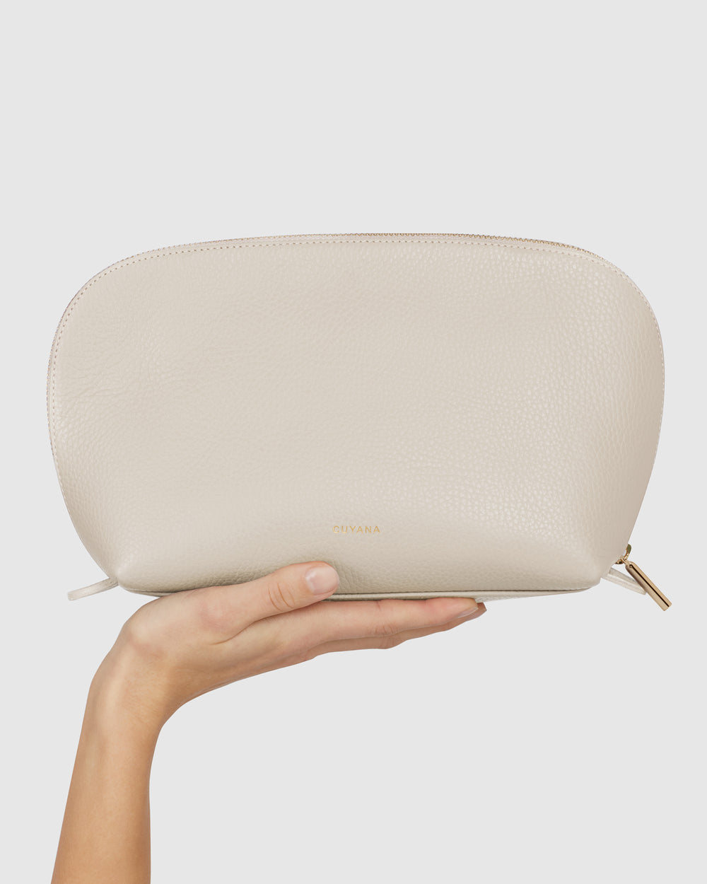 A hand holding a plain clutch bag against a plain background.