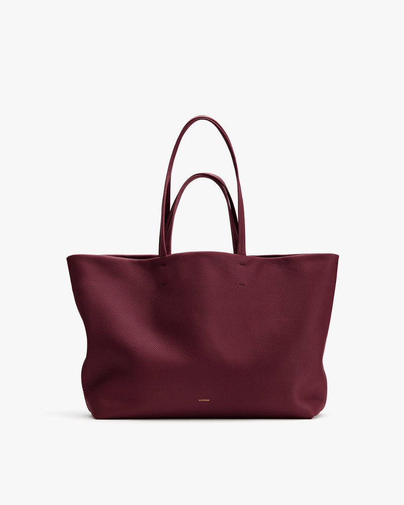 Large tote bag with double handles and subtle branding on the front.