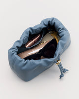 Drawstring pouch open with sunglasses, pen, and wallet inside.