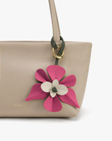 Handbag with floral-shaped leather charm attached to strap.