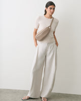 Person wearing a belt bag, light top, and wide-leg pants.