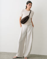 Person wearing a short-sleeve shirt, wide pants, sandals, and a belt bag.
