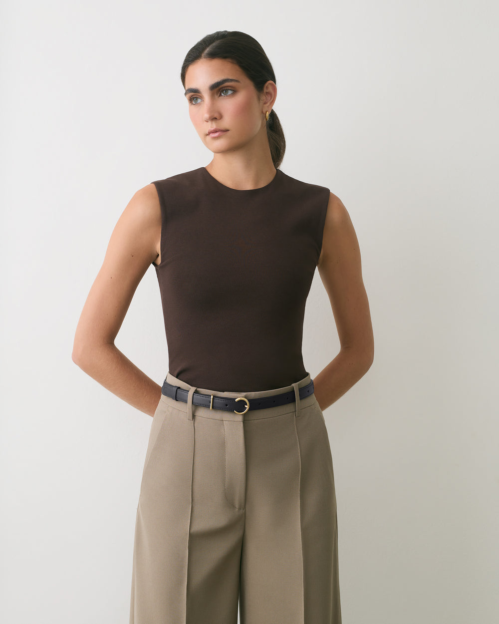 Person wearing sleeveless top and wide-leg pants with belt.