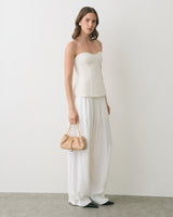 Person wearing strapless top and wide pants, holding small handbag.