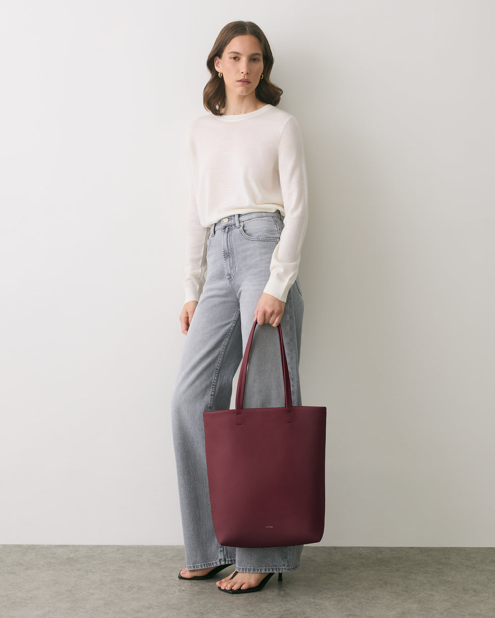 Person standing with a tote bag wearing casual attire.