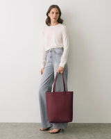 Person standing with a tote bag wearing casual attire.