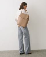 Person in casual outfit holding a large shoulder bag, facing sideways.