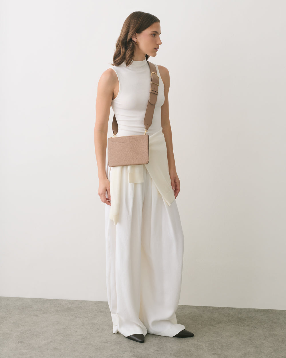 Person in sleeveless top and wide pants with a small rectangular shoulder bag