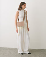 Person in sleeveless top and wide pants with a small rectangular shoulder bag
