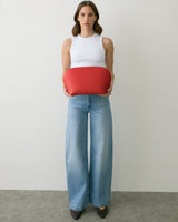 Person holding a round bag, wearing a sleeveless top and wide-leg jeans.