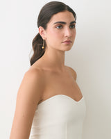 Person wearing a strapless top with drop earrings, looking to the side.