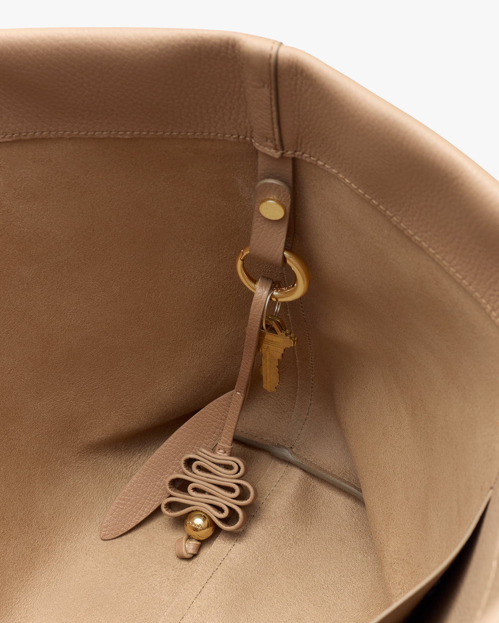 Interior of a bag with attached keychain and decorative charm.