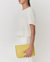 Person holding a rectangular clutch bag against their side.