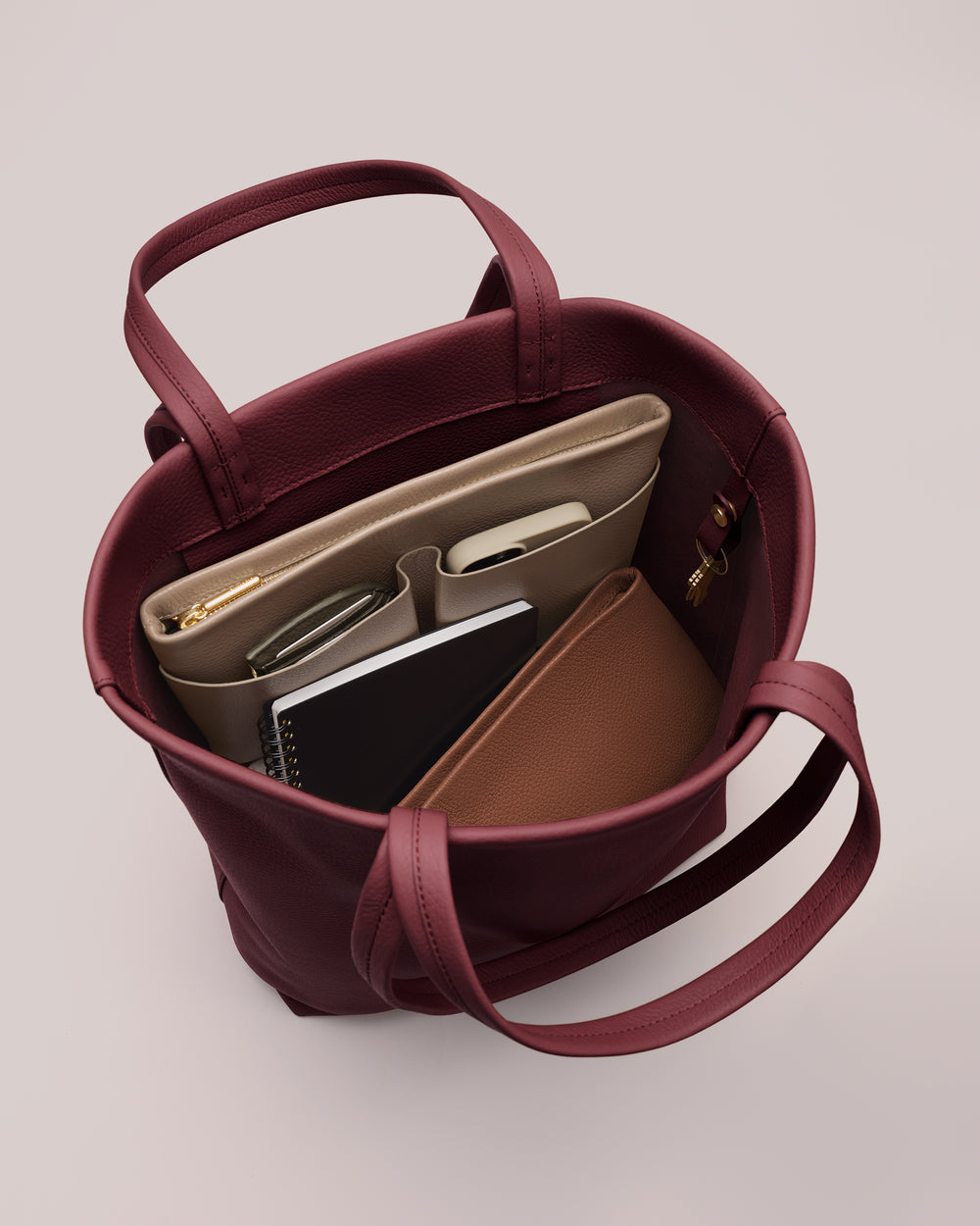 Open handbag with organized items inside, including a laptop and notebook.