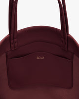 Round bag with long handles and an exterior pocket.