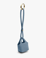 Small handbag with long metal handle ring laying flat.