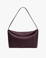 Handbag with curved top and single strap on white background