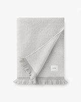 Folded fringed blanket with visible label.