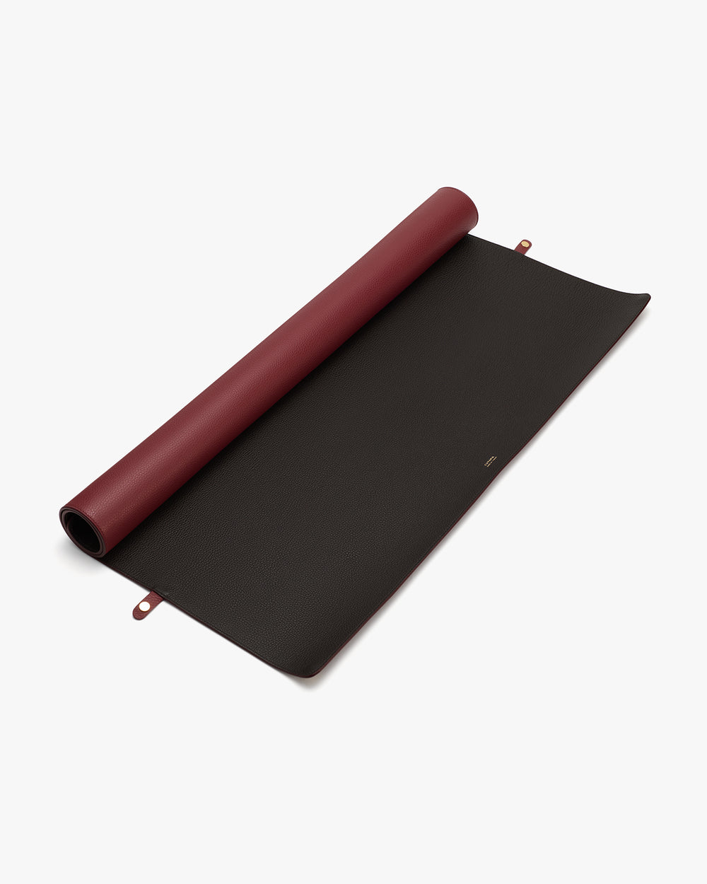 Rolled yoga mat partially unrolled on a surface.