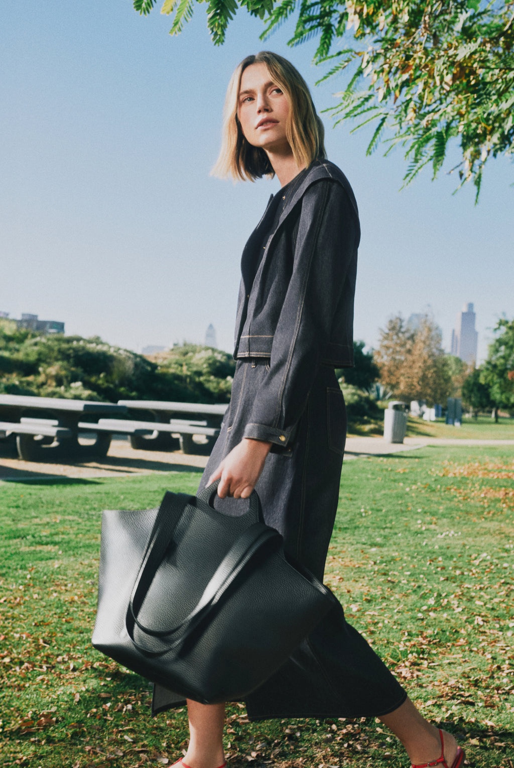 Person walking in park carrying a large tote bag