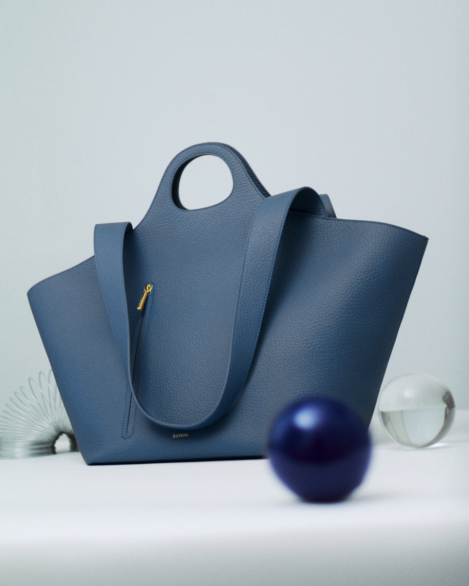 Handbag with round handle on a table with decorative objects.