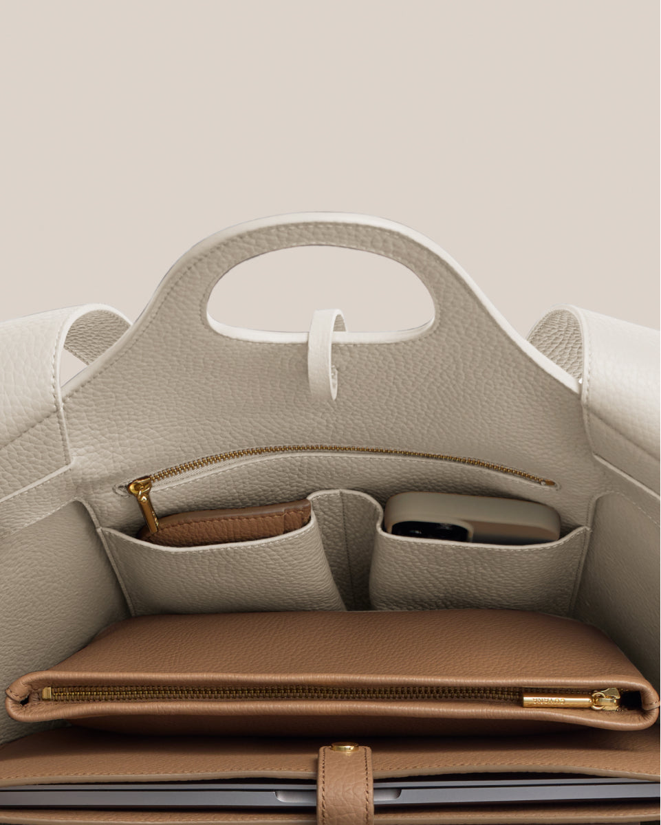 Open handbag displaying compartments with a phone and a wallet inside.