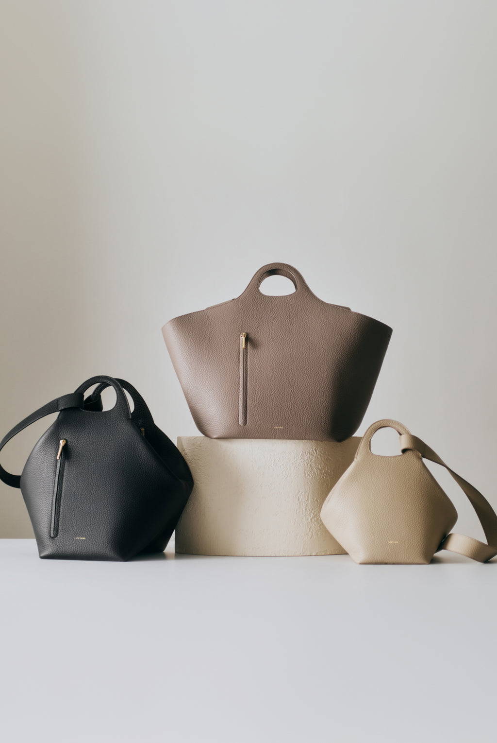 Three handbags displayed on tiered platforms.