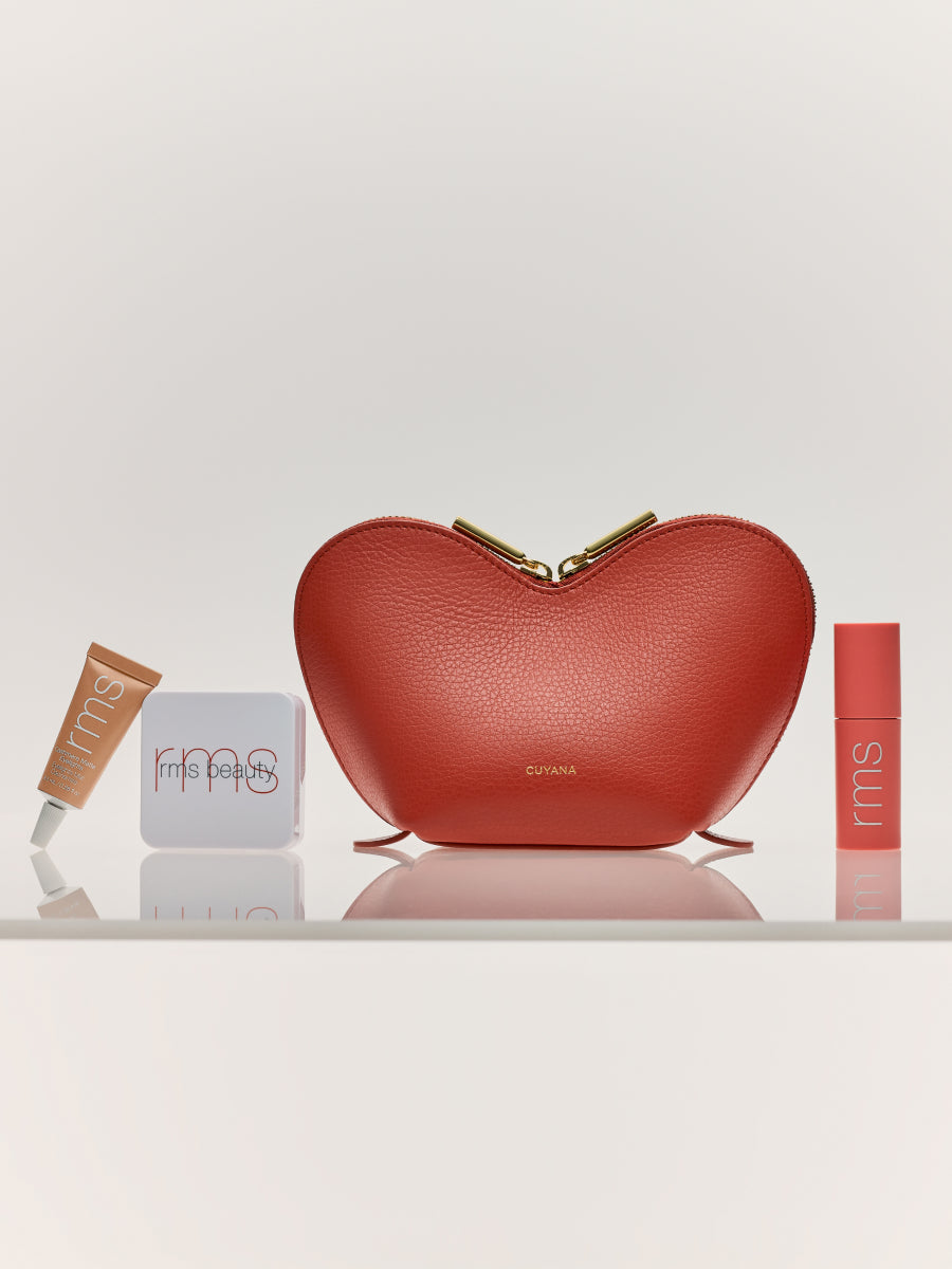 Heart-shaped pouch with makeup items placed around it on a shelf.