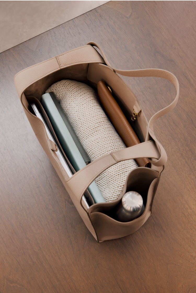Top view of an open tote bag with books and a thermos inside.