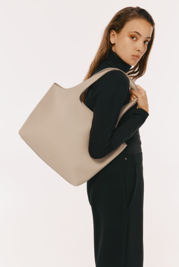Woman carrying a large bag over her shoulder looking back.