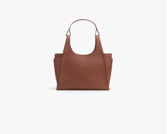 Handbag with a wide handle and side pockets on a plain background.