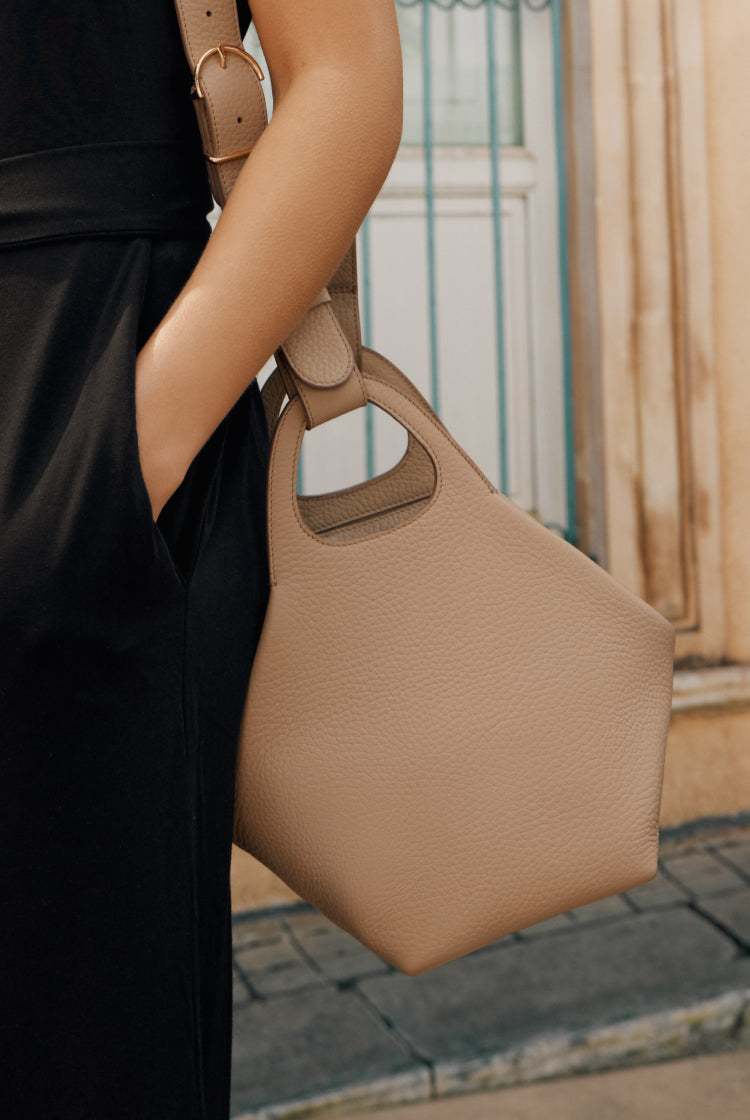 Person holding a geometric handbag with one hand in pocket.