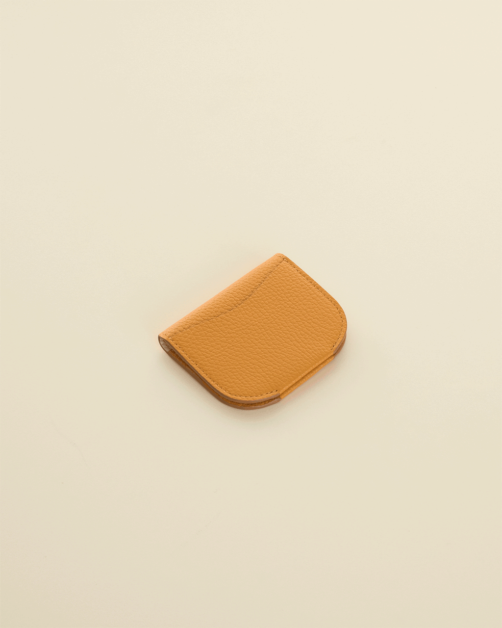 Small leather card holder on a plain surface.