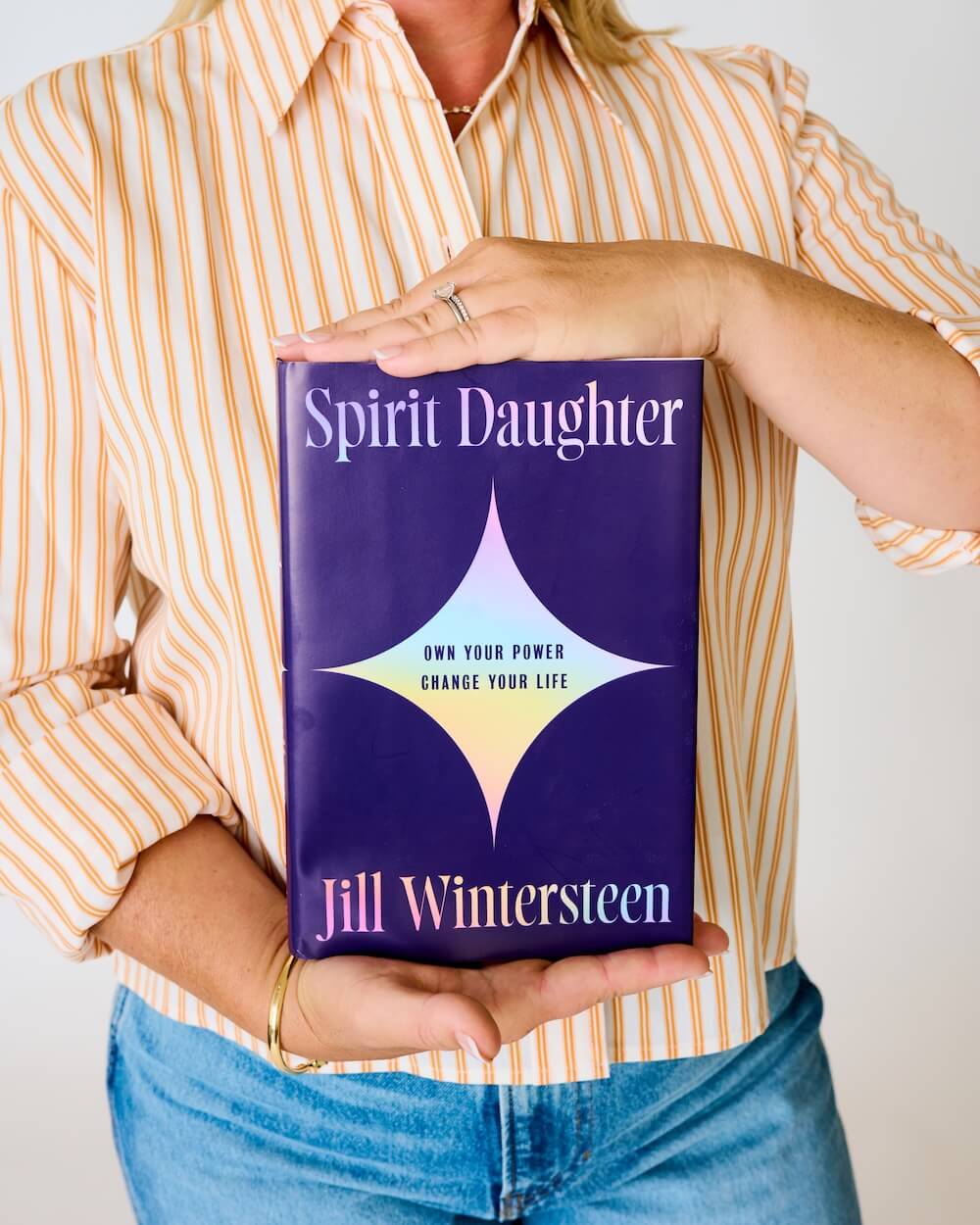 Person holding a book titled Spirit Daughter by Jill Wintersteen.
