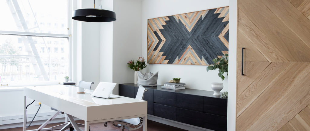 Modern office with a desk, chairs, couch, and a large wall art.