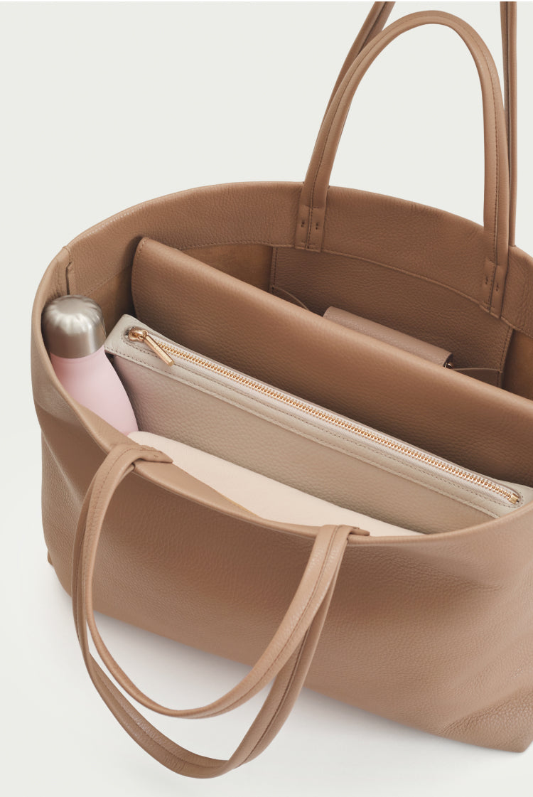 Open handbag showing interior compartments and contents including a flask.