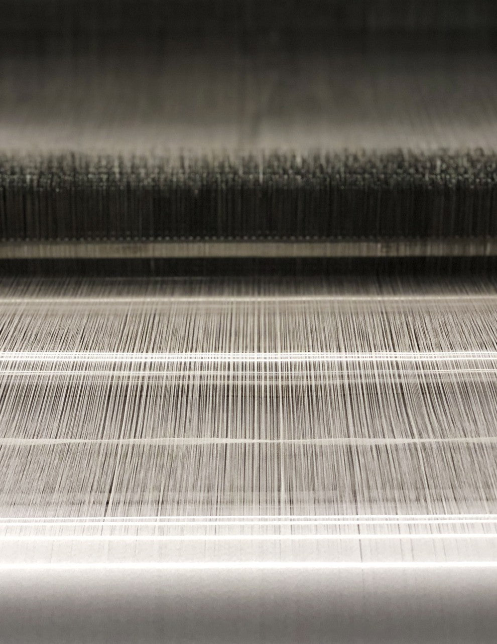 Close-up view of multiple layers of textured threads on a loom.
