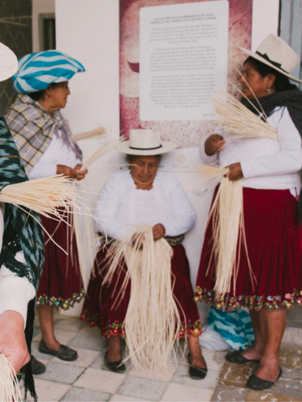 Four people standing and sitting while handling long fibrous materials.