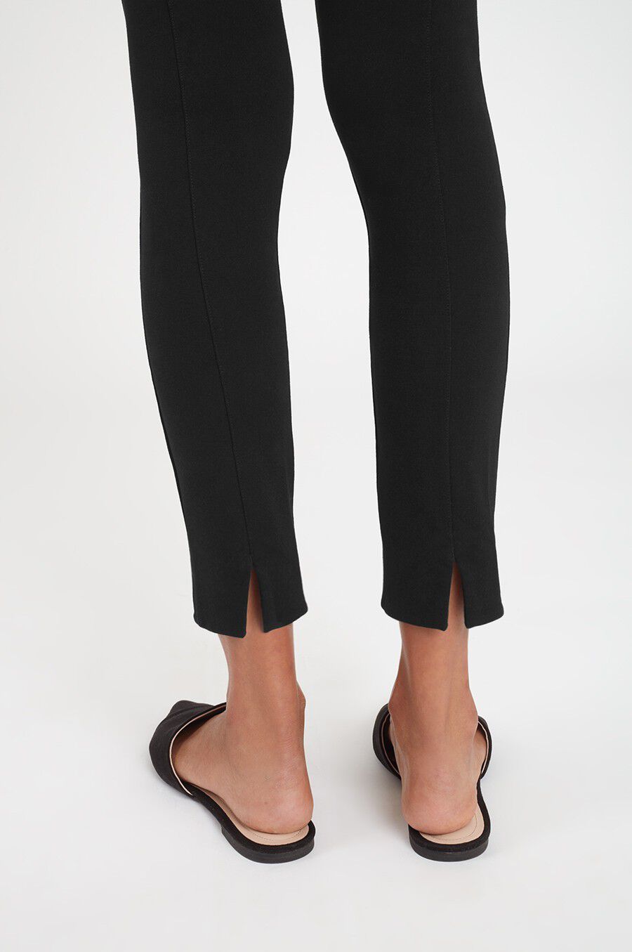 Person wearing pants and heeled shoes, view cropped at the calves.