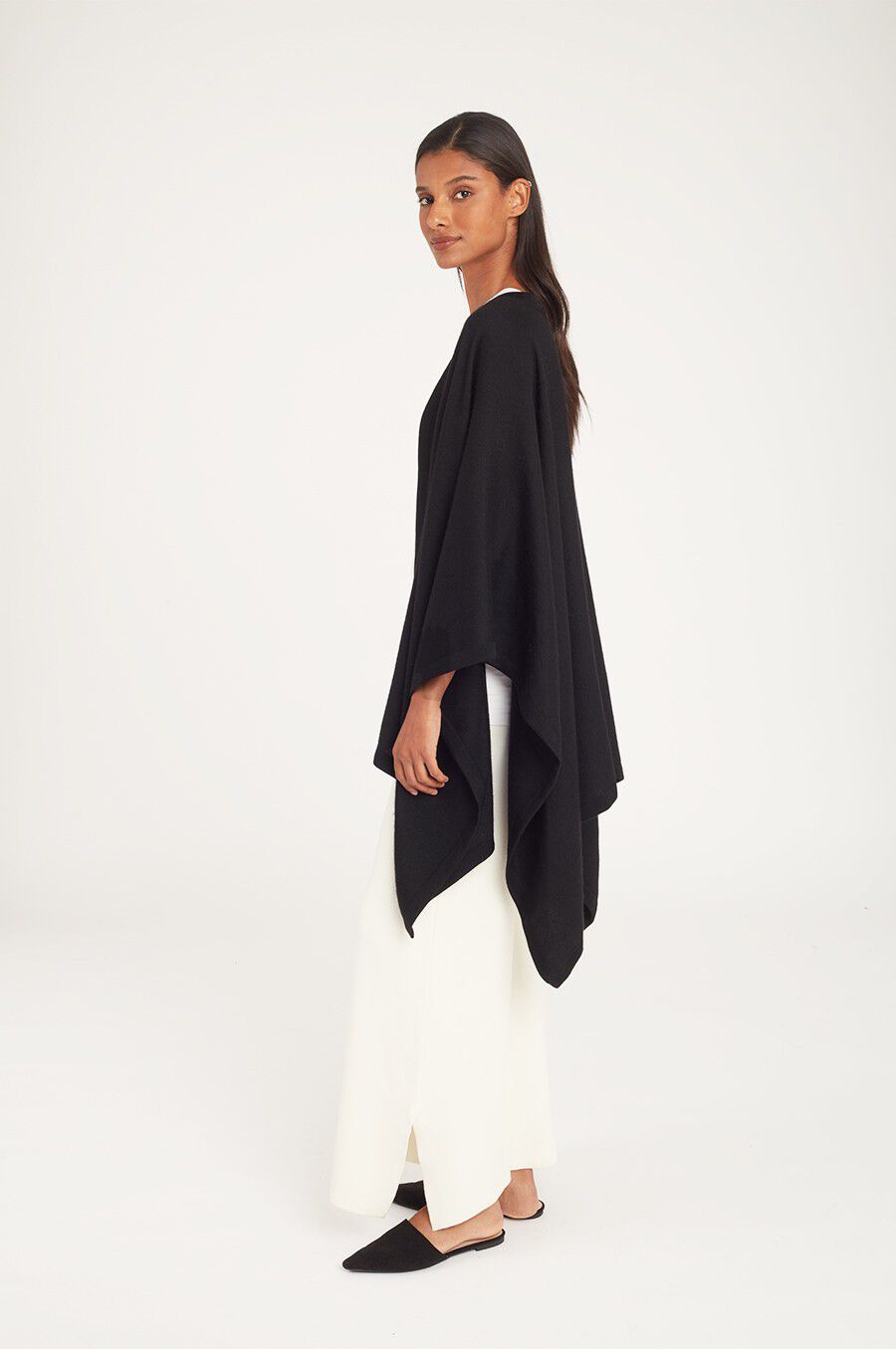 Woman in a long-sleeve top and wide-leg pants standing side view.