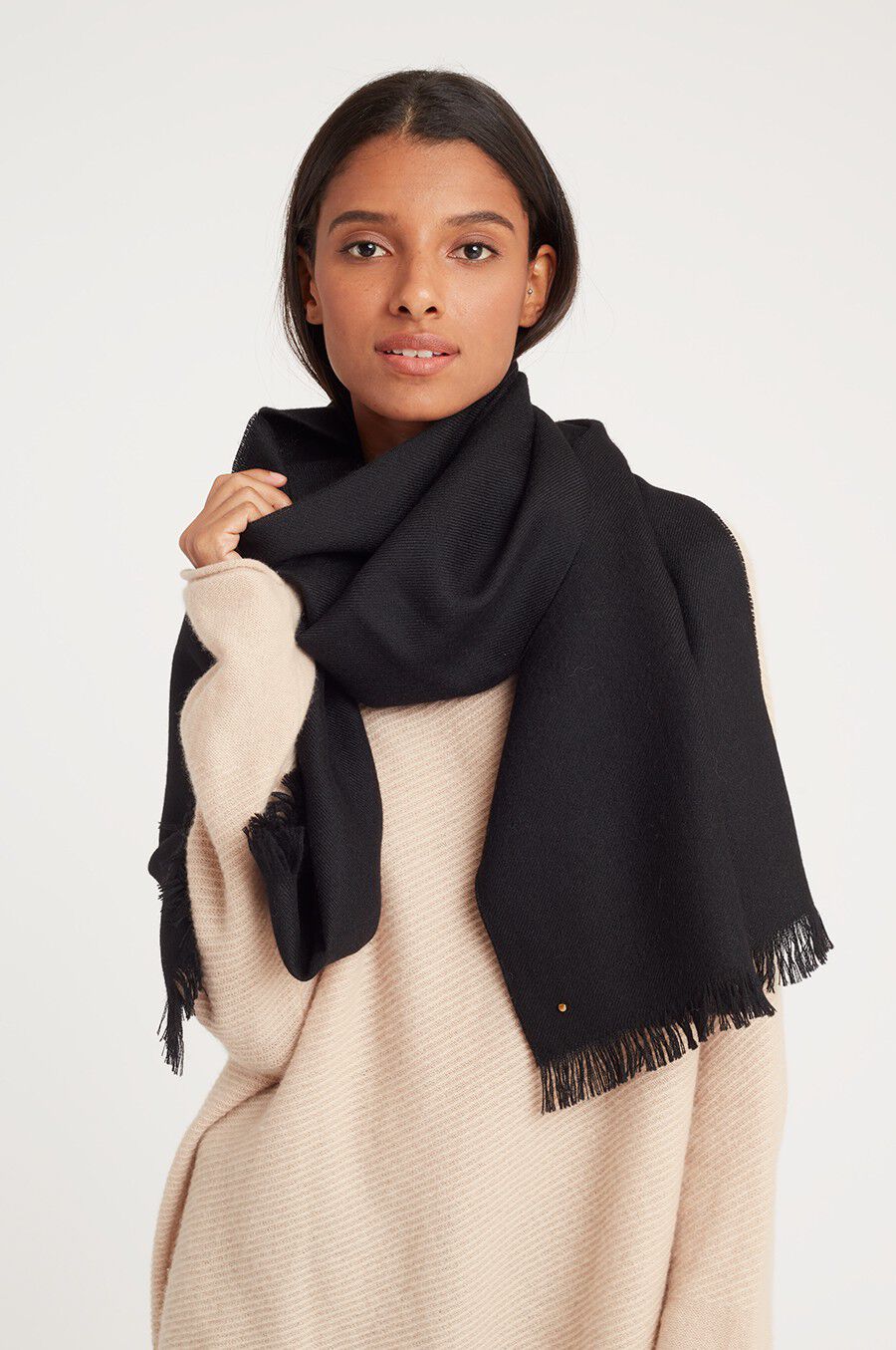 Woman wearing a large scarf over a sweater, looking at the camera.