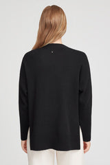 Woman seen from behind wearing a long-sleeve sweater and pants.