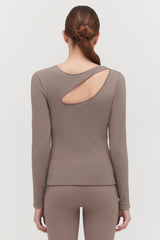 Woman facing away, wearing a top with a back cut-out and hair in a bun.