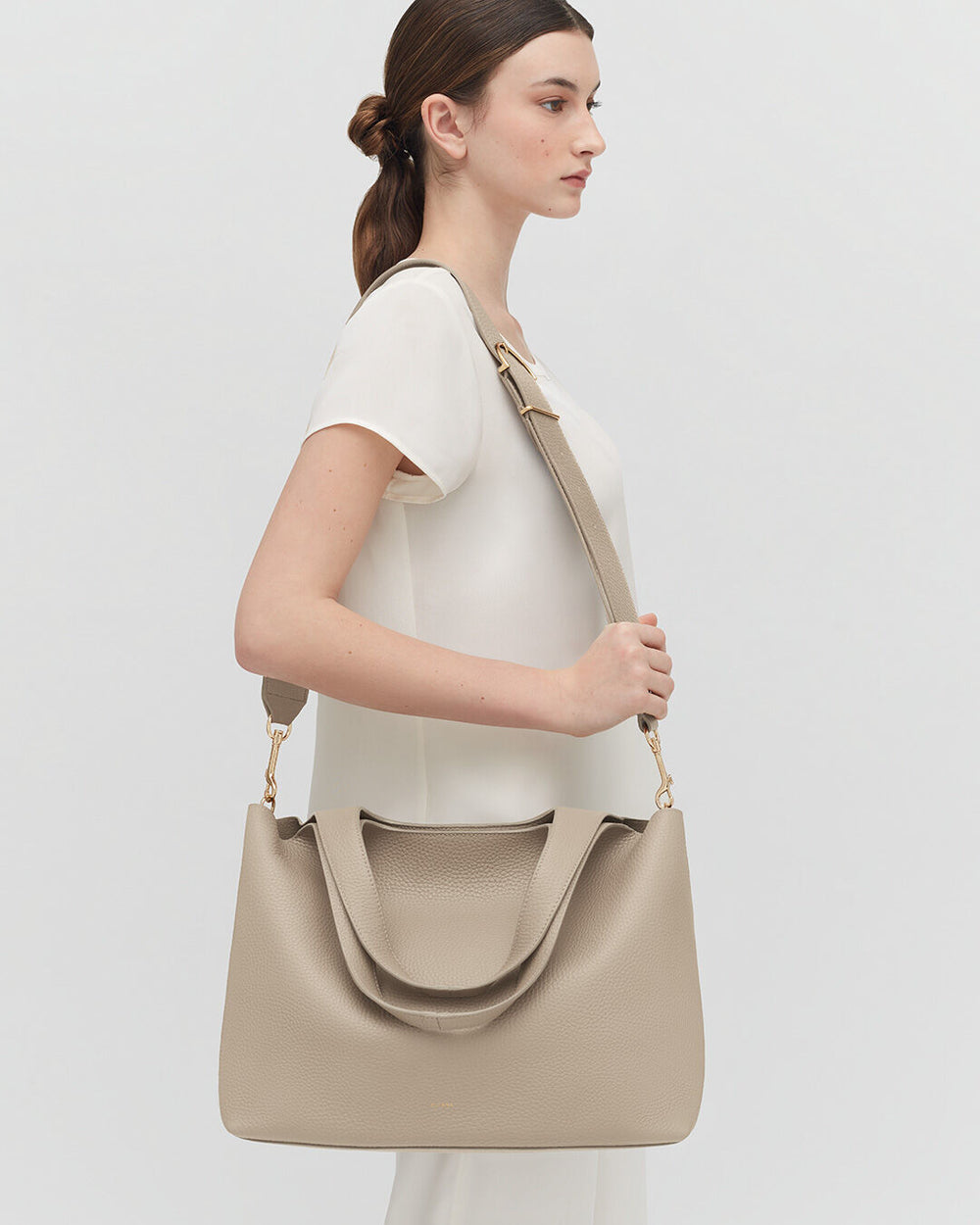 Woman in profile carrying a large handbag over her shoulder.