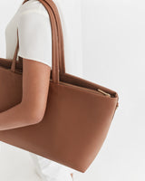 Person holding a large handbag over the shoulder.
