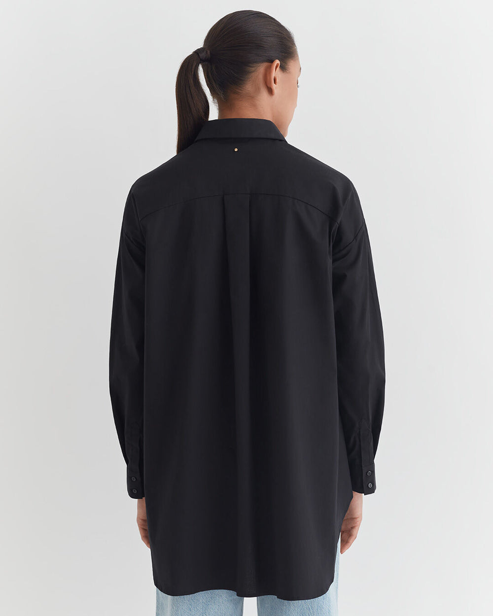 Person seen from behind wearing a long-sleeved shirt and jeans.